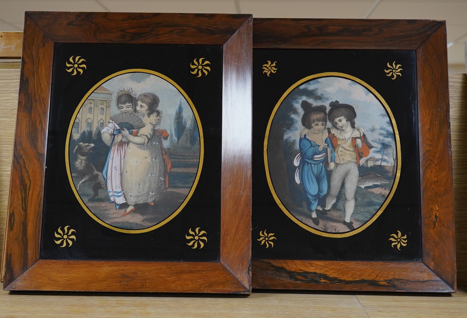 Early 19th century, pair of Verre eglomise prints, Children before landscapes, each 24 x 19cm. Condition - fair, some losses to the frame